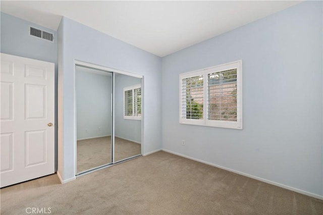 unfurnished bedroom featuring baseboards, carpet flooring, visible vents, and a closet