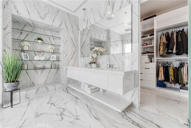 bathroom with marble finish floor, stone wall, and a spacious closet