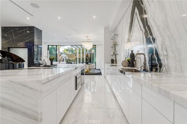 kitchen with stone wall, marble finish floor, a sink, and modern cabinets