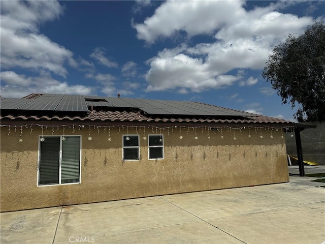view of home's exterior featuring roof mounted solar panels, a patio, and stucco siding