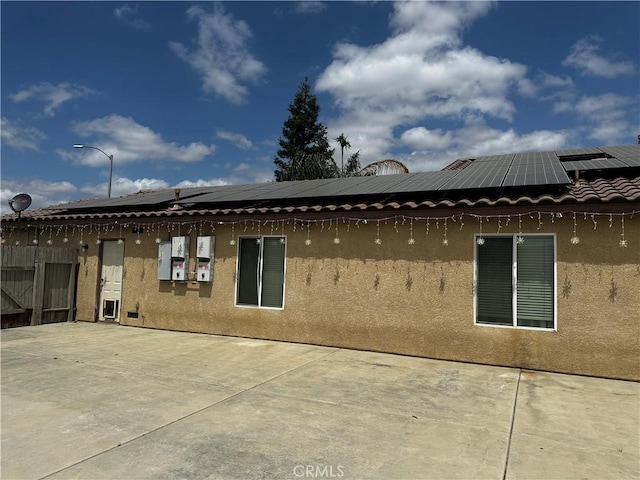 back of property featuring a patio, solar panels, and stucco siding