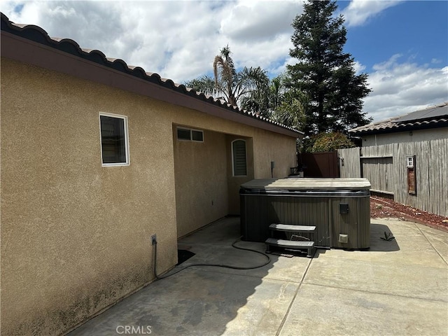view of patio / terrace featuring fence and a hot tub