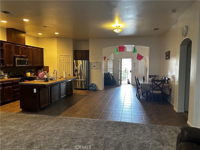 kitchen with arched walkways, visible vents, stainless steel appliances, and dark tile patterned flooring