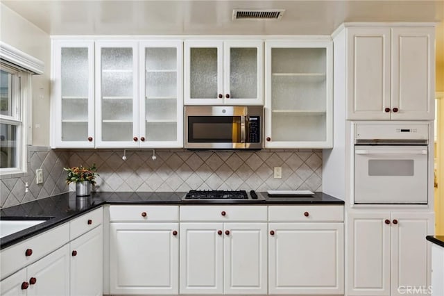 4254 Miramonte Pl, Riverside, CA 92501 - kitchen with stainless steel appliances, dark countertops, white cabinets, and backsplash