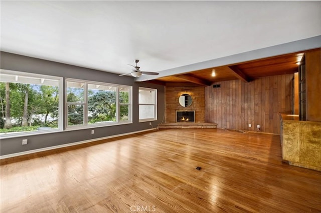 4254 Miramonte Pl, Riverside, CA 92501 - unfurnished living room with wood walls, plenty of natural light, wood finished floors, a ceiling fan, and a stone fireplace