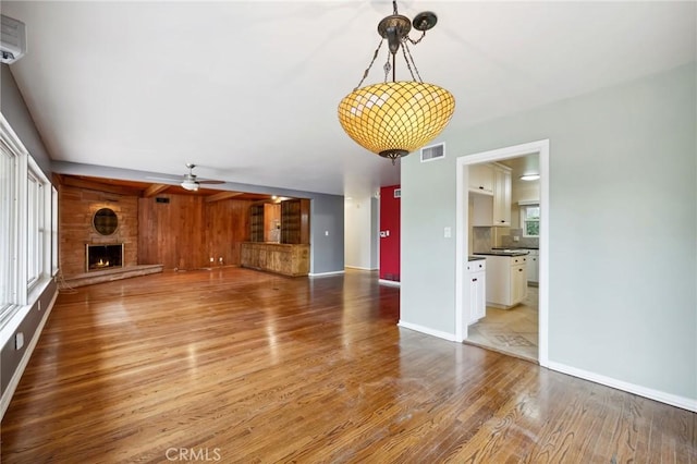 4254 Miramonte Pl, Riverside, CA 92501 - unfurnished living room with wood finished floors, a ceiling fan, a large fireplace, baseboards, and wood walls