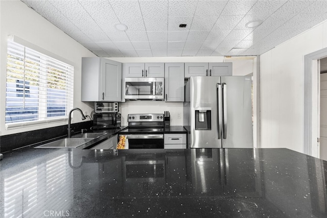 10638 Pine Dr, Wofford Heights, CA 93285 - kitchen featuring dark stone counters, a sink, appliances with stainless steel finishes, and gray cabinetry