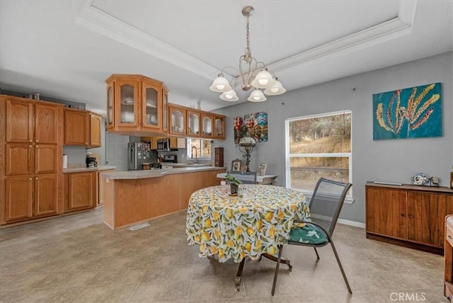 dining space featuring a raised ceiling, a notable chandelier, crown molding, and baseboards