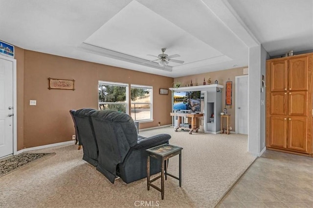 living room with light carpet, baseboards, a ceiling fan, and a raised ceiling