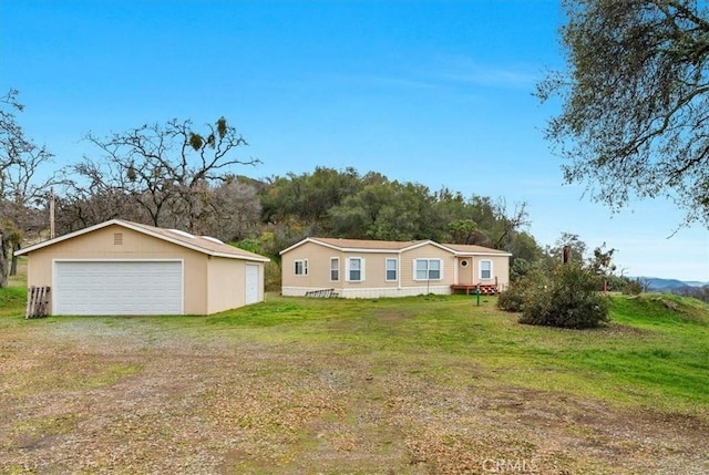 manufactured / mobile home featuring a front lawn, an outbuilding, and a garage