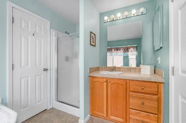 bathroom with a stall shower, tile patterned floors, and vanity