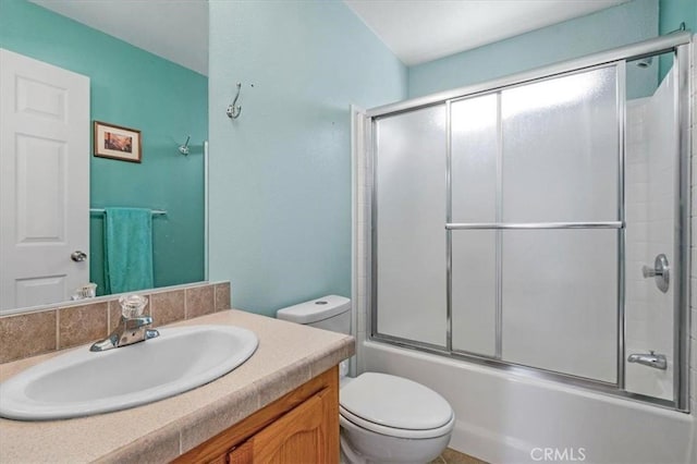 bathroom with toilet, vanity, and combined bath / shower with glass door