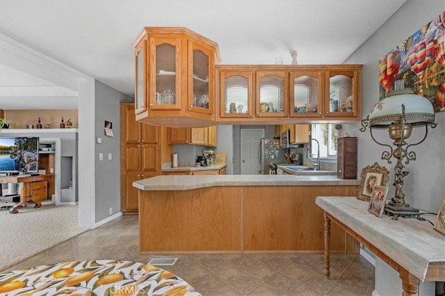 kitchen featuring light countertops, a peninsula, glass insert cabinets, and visible vents