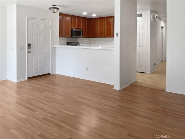 15605 Lasselle St Unit 6, Moreno Valley, CA 92551 - kitchen featuring stainless steel microwave, light wood-style floors, range, and baseboards