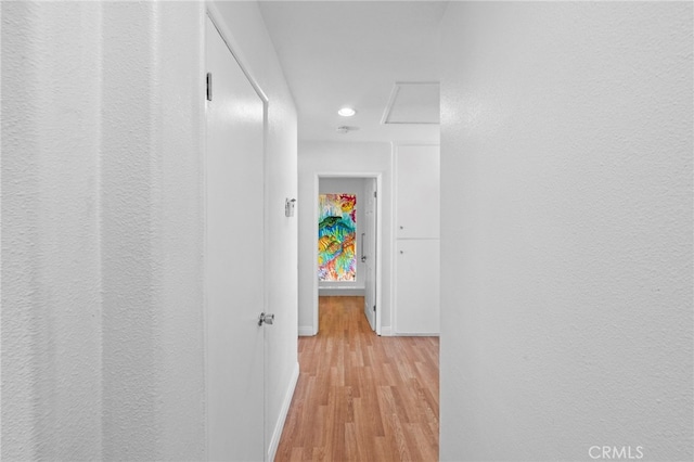 hallway featuring attic access, baseboards, recessed lighting, and light wood-style flooring