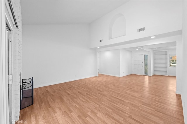 unfurnished living room with baseboards, built in features, visible vents, and light wood-type flooring