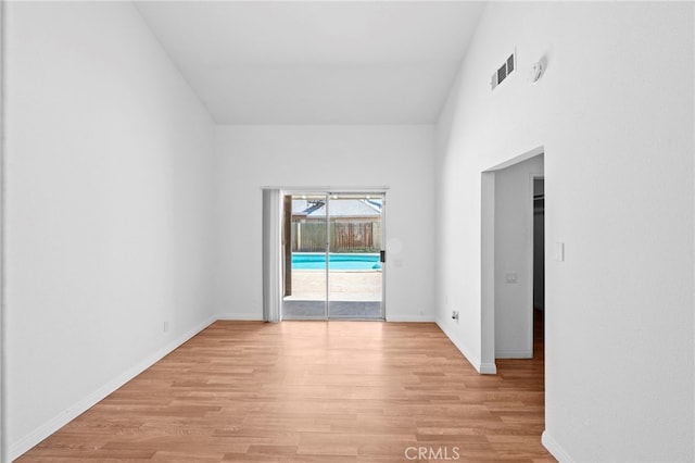 empty room featuring light wood finished floors, baseboards, and visible vents
