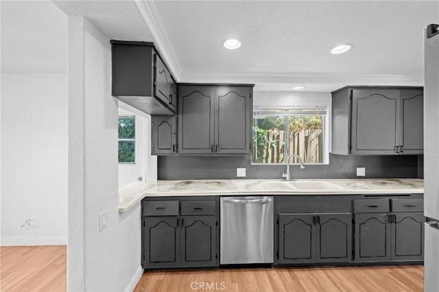 kitchen with stainless steel dishwasher, a sink, light wood finished floors, and light countertops