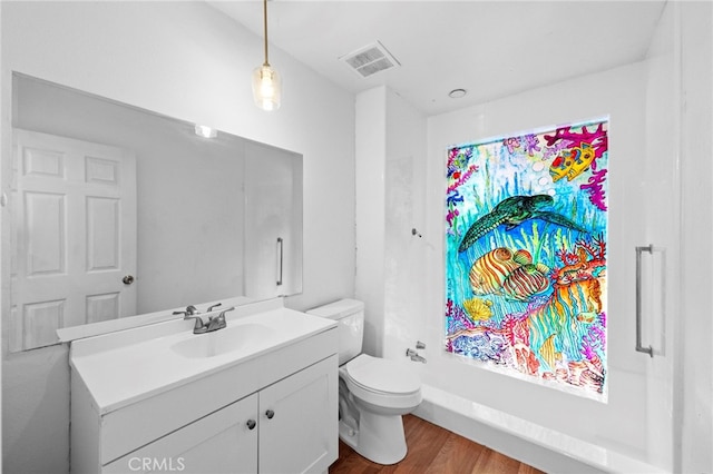 bathroom with toilet, vanity, wood finished floors, and visible vents