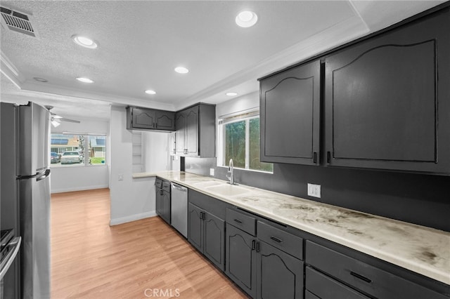 kitchen with a sink, light countertops, stainless steel appliances, light wood-style flooring, and visible vents