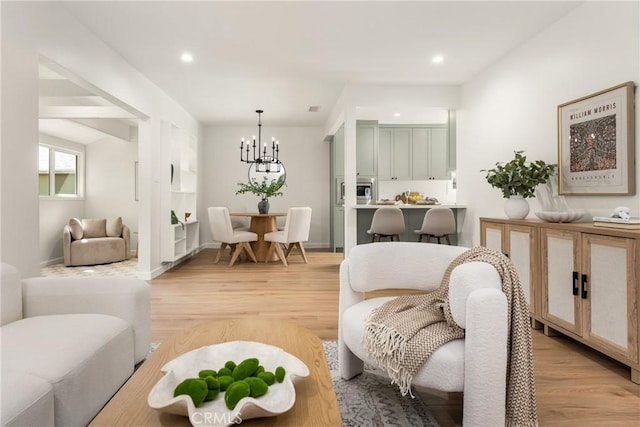 living room featuring baseboards, an inviting chandelier, recessed lighting, and light wood-type flooring