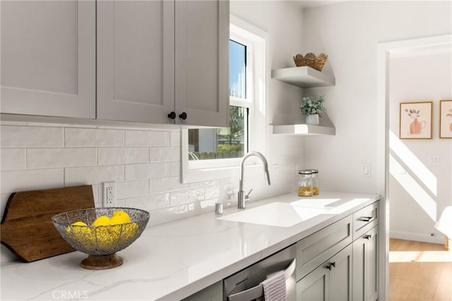 kitchen featuring a sink, open shelves, backsplash, and light stone counters