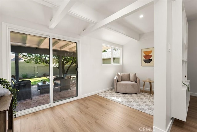 living area featuring lofted ceiling with beams, baseboards, and wood finished floors