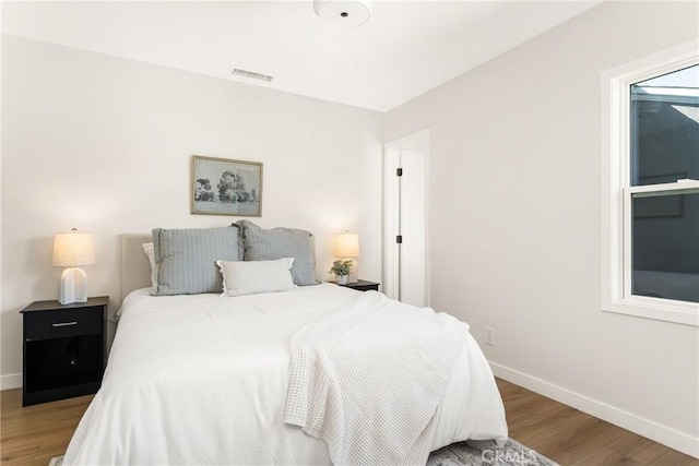 bedroom featuring visible vents, baseboards, and wood finished floors