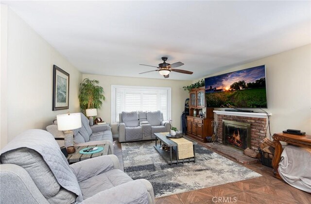 living room featuring ceiling fan and a brick fireplace