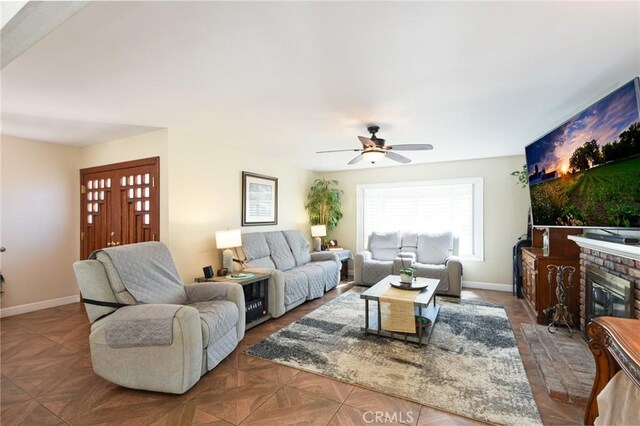 living room with baseboards, ceiling fan, and a fireplace