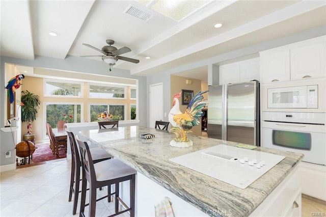 kitchen with white cabinetry, visible vents, light stone countertops, and white appliances