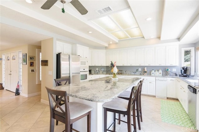 kitchen featuring light tile patterned flooring, visible vents, light stone countertops, stainless steel appliances, and a kitchen breakfast bar
