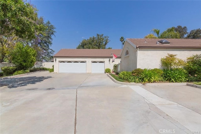 view of side of home with a tiled roof, a garage, driveway, and stucco siding