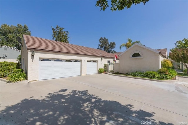 exterior space featuring an attached garage, a tile roof, concrete driveway, and stucco siding