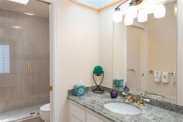 bathroom featuring toilet, vanity, and a stall shower