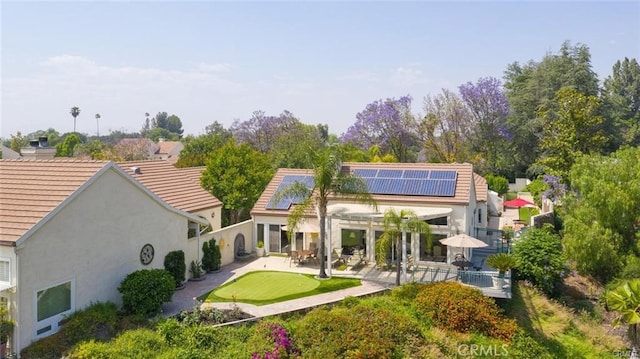 back of property featuring a patio, a tile roof, roof mounted solar panels, and stucco siding