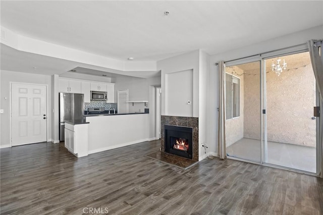 unfurnished living room with a sink, baseboards, a fireplace, and dark wood finished floors