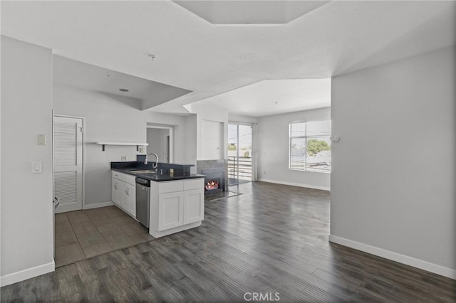kitchen with open floor plan, dishwasher, a sink, and baseboards
