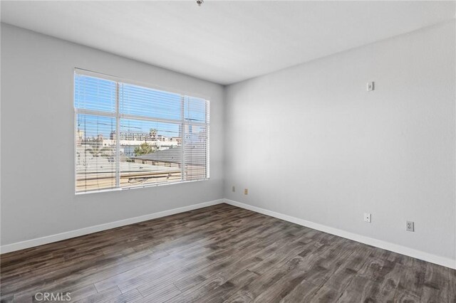 spare room with dark wood-type flooring and baseboards