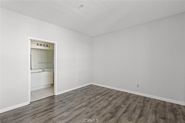 unfurnished bedroom with baseboards, a sink, and wood finished floors