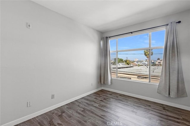 spare room featuring baseboards and wood finished floors