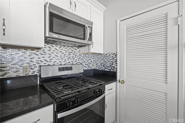 kitchen with tasteful backsplash, appliances with stainless steel finishes, white cabinetry, and dark stone countertops