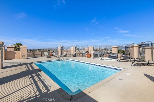 pool with a patio area and fence