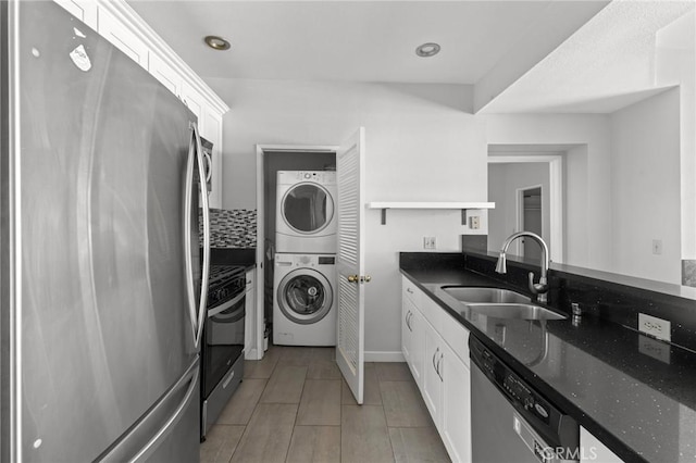 washroom featuring a sink, baseboards, stacked washer / dryer, and laundry area