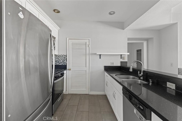 kitchen with dark stone countertops, white cabinets, a sink, stainless steel appliances, and decorative backsplash
