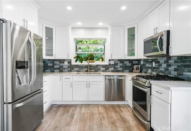 410 Via Mesa Grande, Redondo Beach, CA 90277 - kitchen featuring stainless steel appliances, a sink, light wood finished floors, white cabinets, and tasteful backsplash