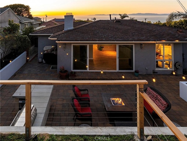 410 Via Mesa Grande, Redondo Beach, CA 90277 - back of property at dusk featuring a patio area, stucco siding, a chimney, and an outdoor fire pit
