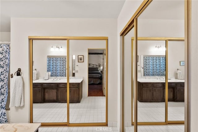 full bathroom with two vanities, a sink, connected bathroom, and tile patterned floors