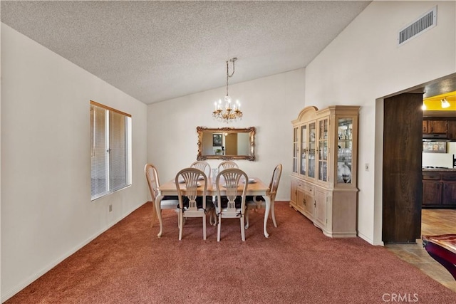 carpeted dining room featuring a textured ceiling, visible vents, a chandelier, and vaulted ceiling