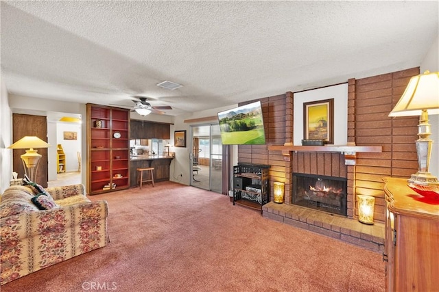 living room with carpet flooring, a textured ceiling, visible vents, a fireplace, and ceiling fan